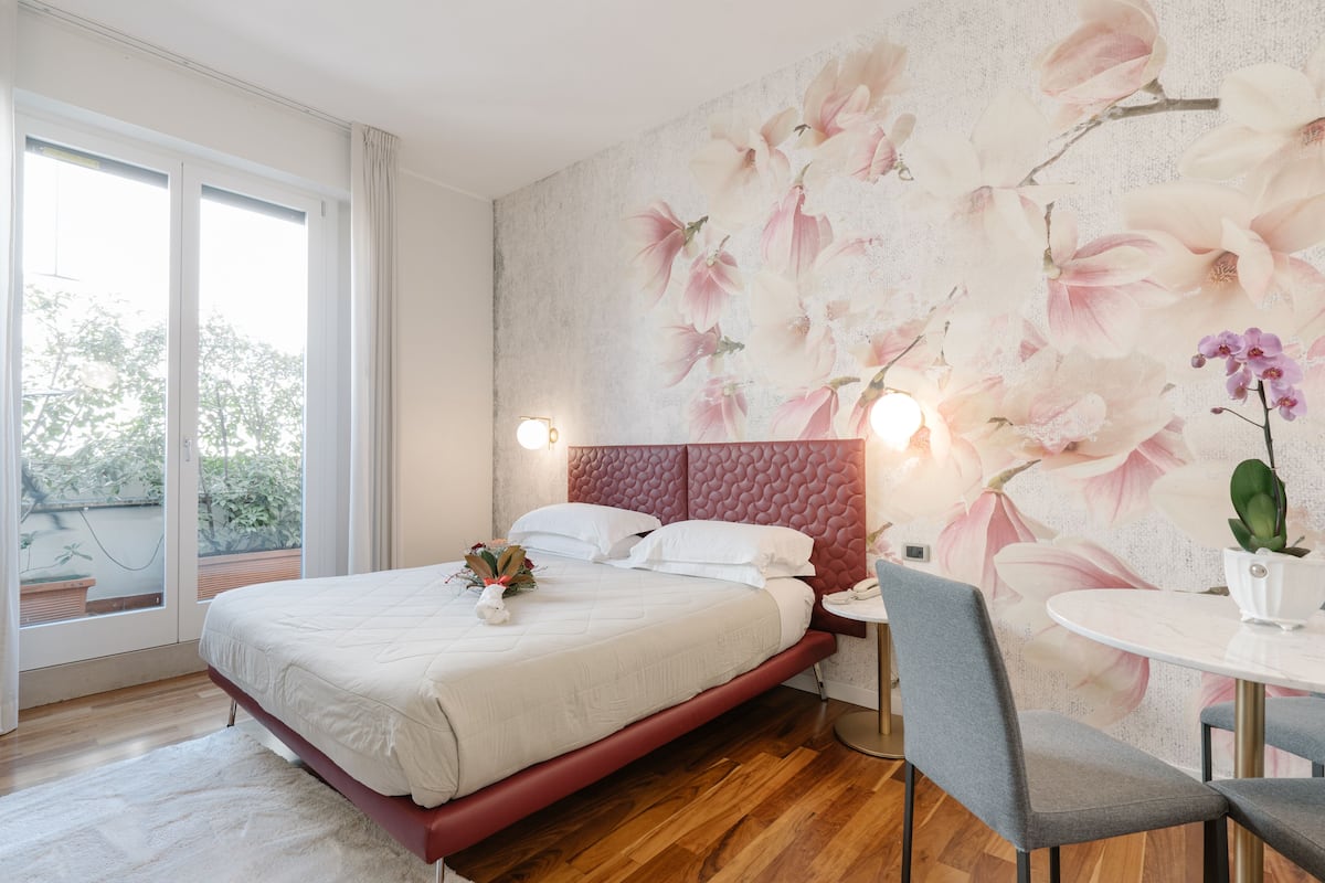 A modern bedroom with a large bed, a small table, and a chair.