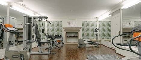 A gym with cardio machines, weight training equipment, and mirrors.