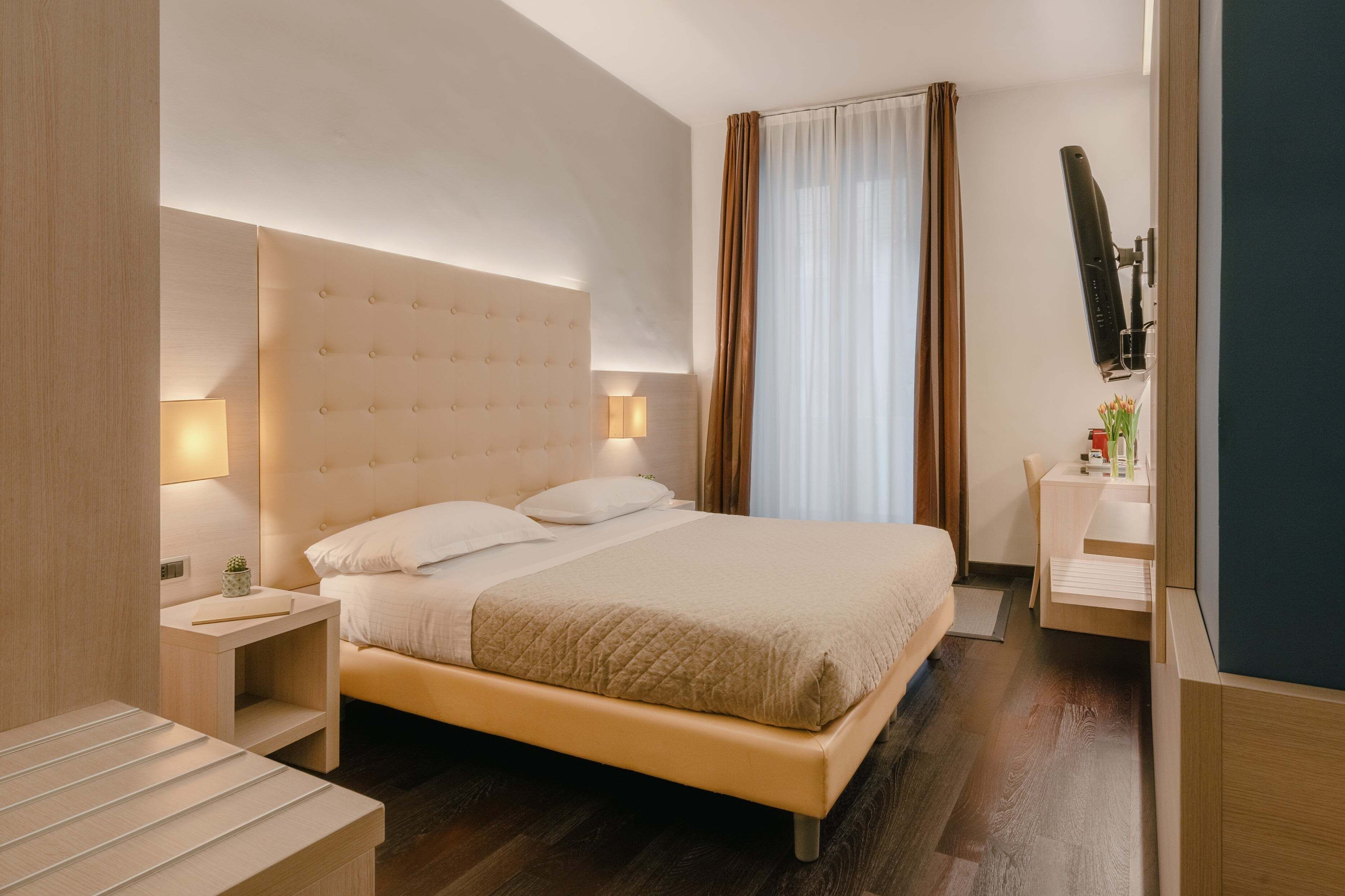 Une chambre d’hôtel avec un grand lit, des tables de chevet, un bureau et un téléviseur.