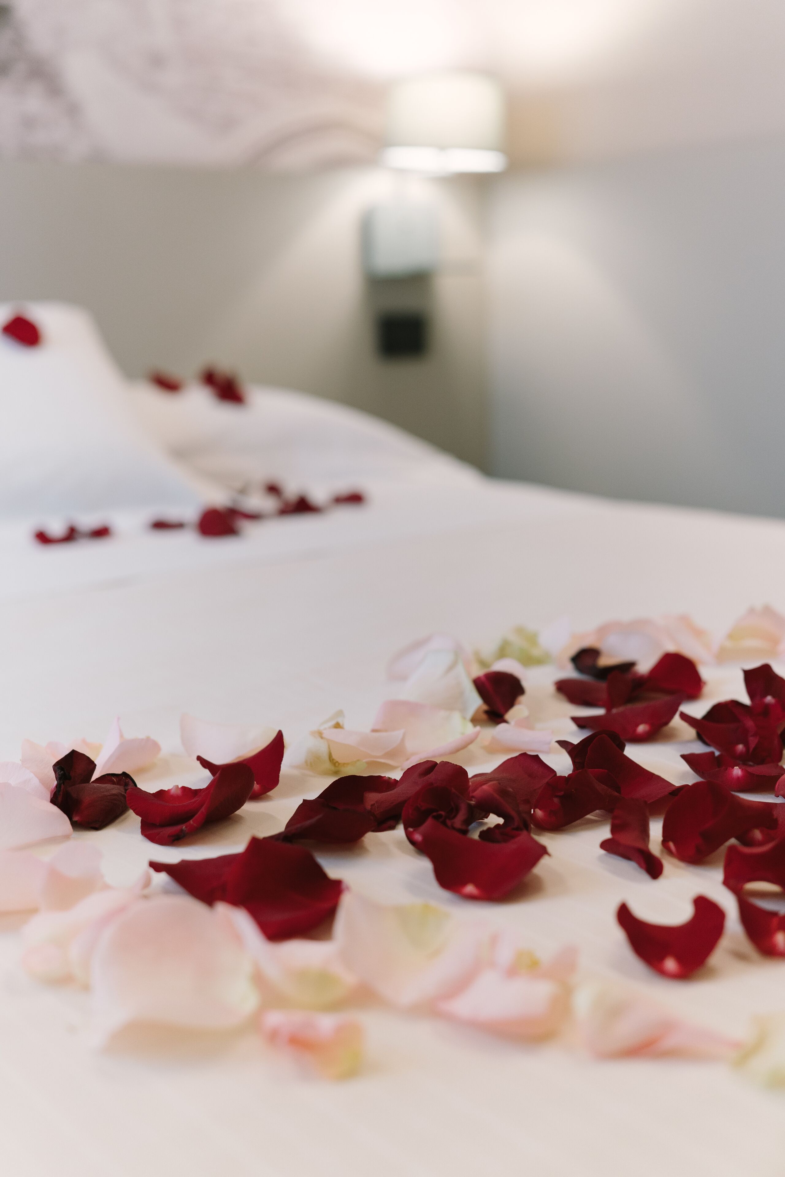 A bed with rose petals scattered on it.