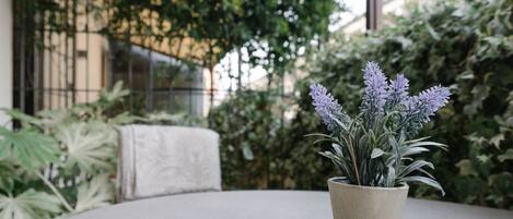 A potted plant on a round table with a view of greenery and a building in the background.