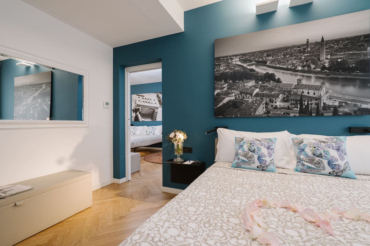 A bedroom with a large bed, a nightstand, and a wall-mounted painting.