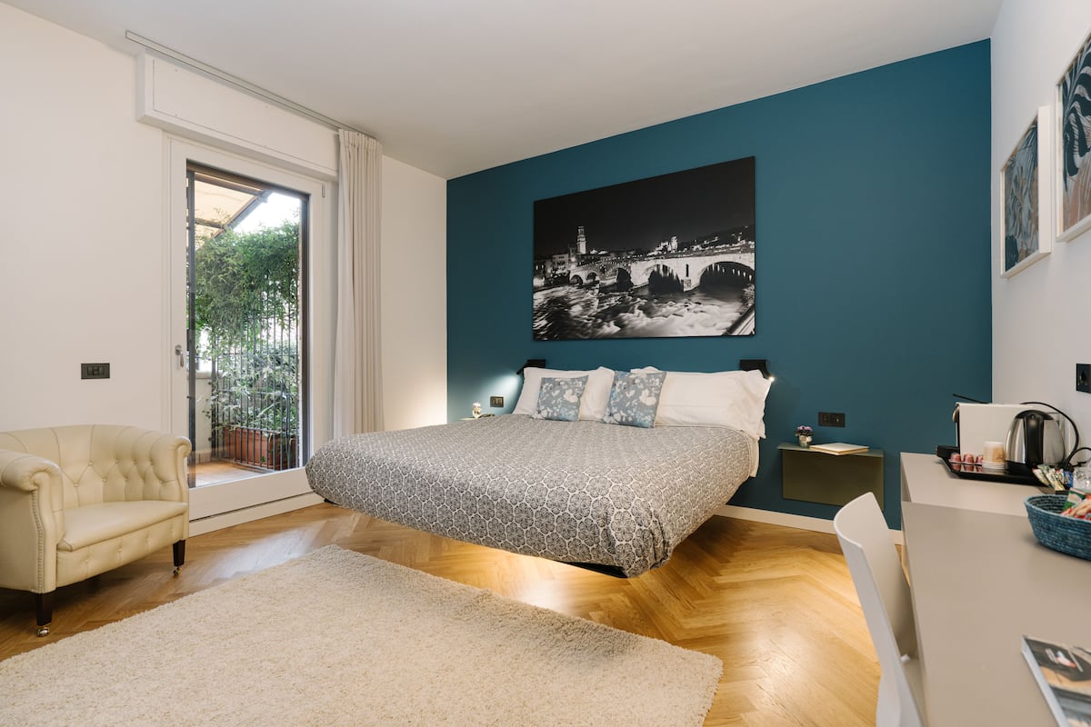 A bedroom with a bed, a chair, a desk, and a large window.