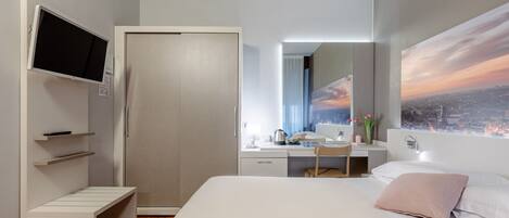 A modern hotel room with a bed, a desk, a chair, a TV, and a cityscape view.
