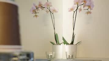 Una mesa blanca con dos orquídeas en macetas, un vaso y un libro titulado "Vera".