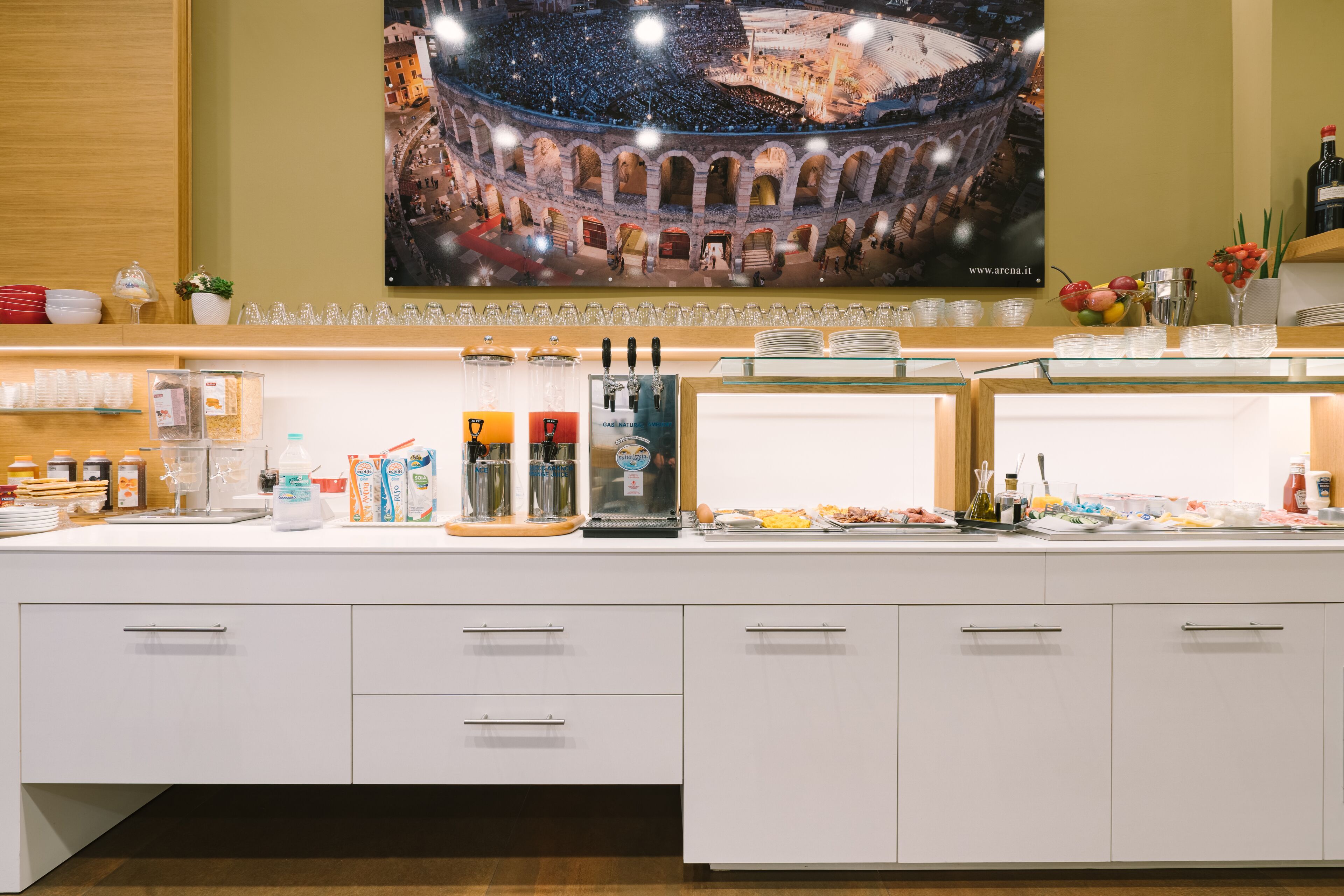 Un espace buffet proposant une variété de plats, de verrerie et une grande affiche représentant un bâtiment historique.
