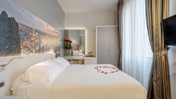 A hotel room with a large bed, a desk, a chair, a television, and a view of a cityscape.