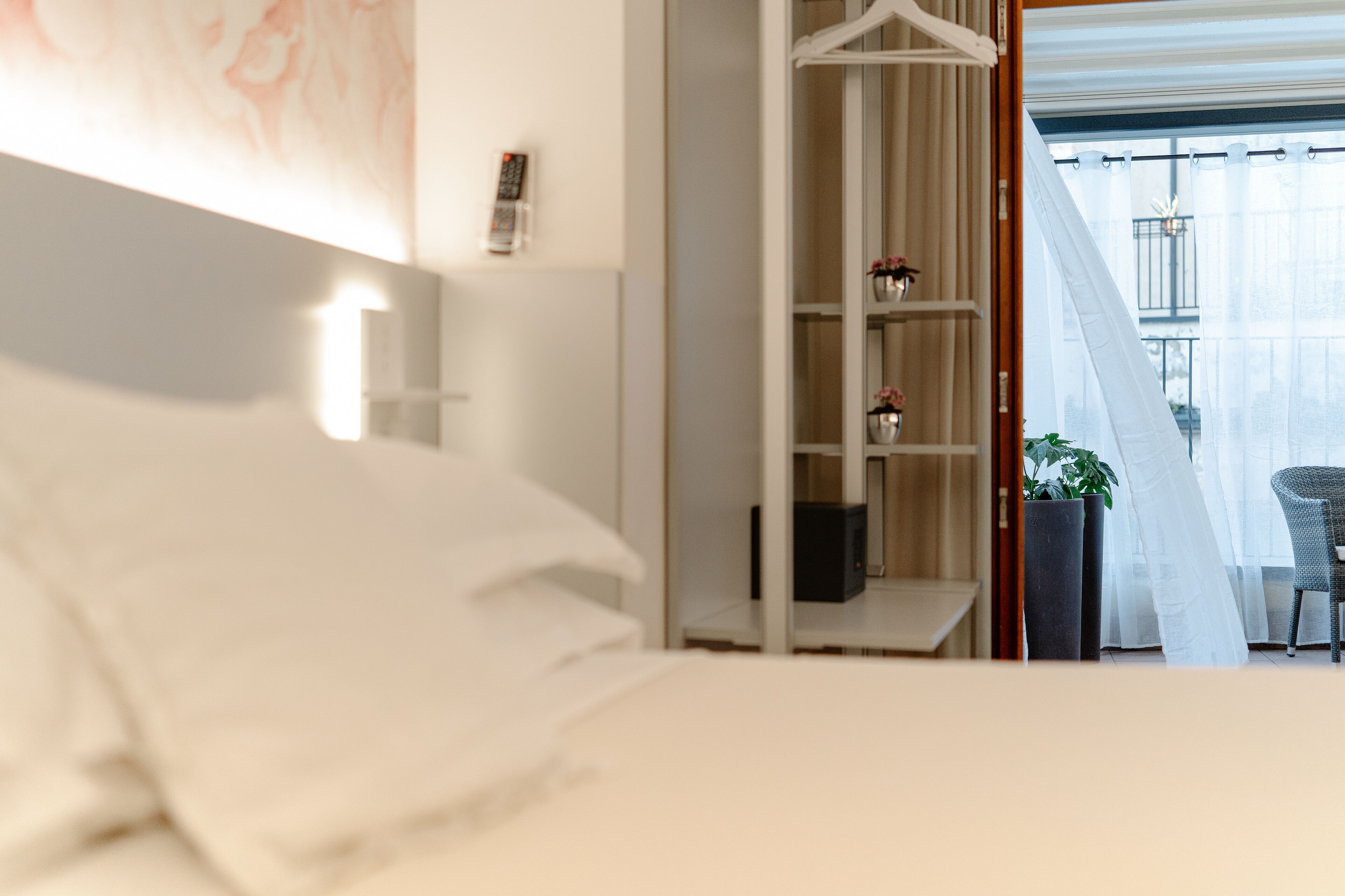 A hotel room with a bed, a wardrobe, and a balcony with a chair.