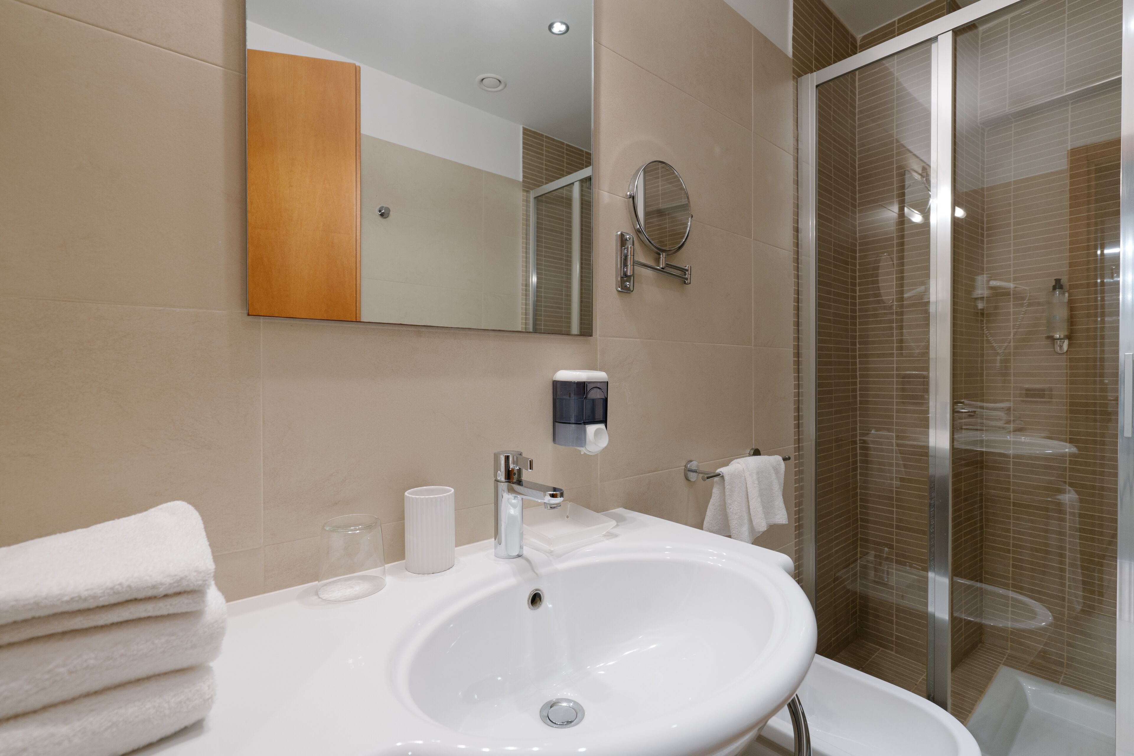 Un baño moderno con un lavamanos grande, un espejo y una cabina de ducha de vidrio.