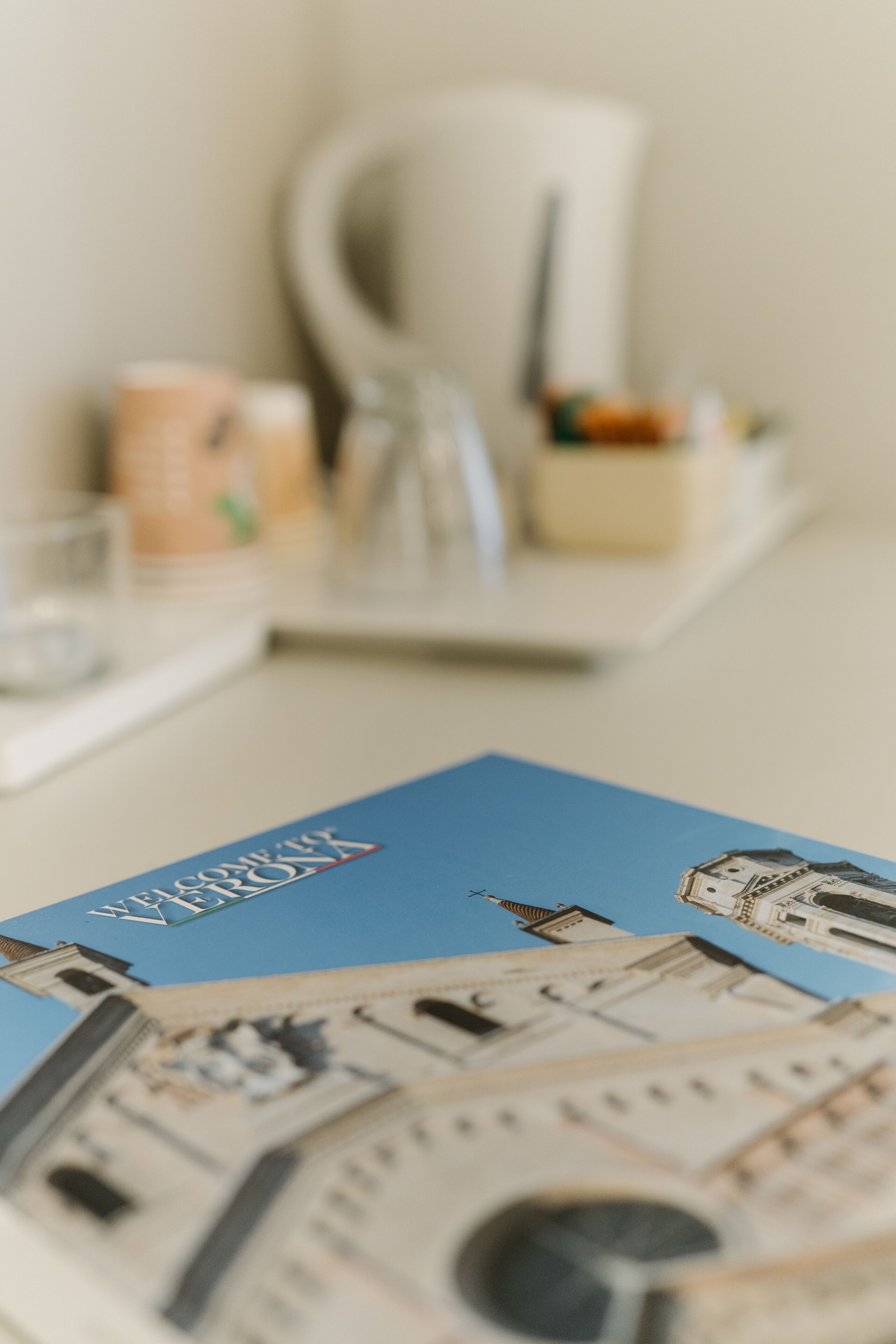 A brochure with architectural illustrations, a coffee machine, and a glass container on a table.