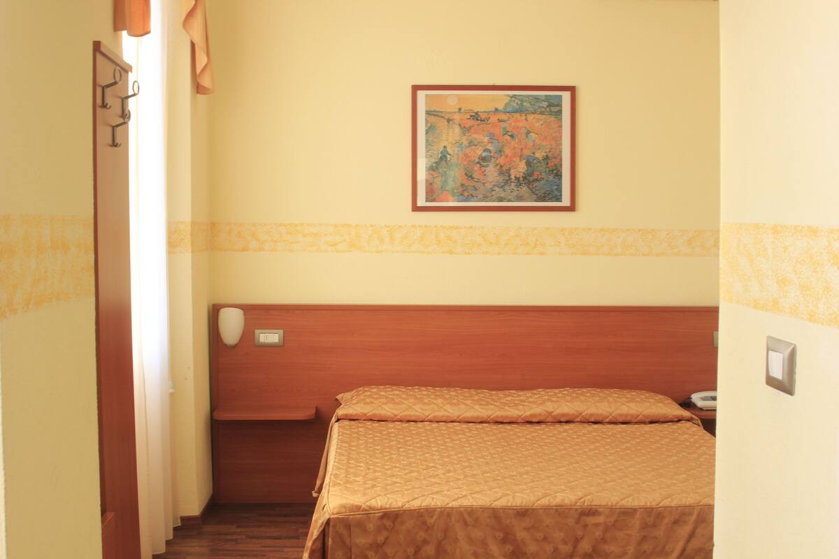 Une chambre d’hôtel avec un lit, un tableau au mur et une tête de lit en bois.
