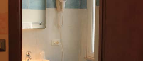 Un baño con lavamanos, espejo, secador de pelo y paredes de azulejos azules.
