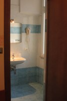 Ein Badezimmer mit Waschbecken, Spiegel, Fön und blauen Fliesen.