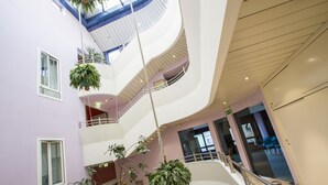 A multi-level atrium with hanging plants, railings, and a modern architectural design. - Hotel Sirena (Cesenatico)