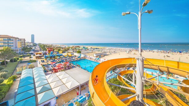 A water park with a large slide, pool area, and beach. - Hotel Sirena (Cesenatico)