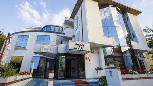 A modern building with a restaurant sign, large windows, and a curved facade. - Hotel Sirena (Cesenatico)