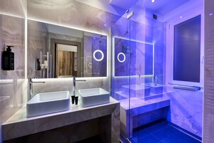 Een moderne badkamer met twee wasbakken, een glazen douchecabine en een grote spiegel.