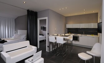 Une chambre d’hôtel moderne équipée d’un lit, d’un bureau avec une chaise, d’une kitchenette et d’un téléviseur.