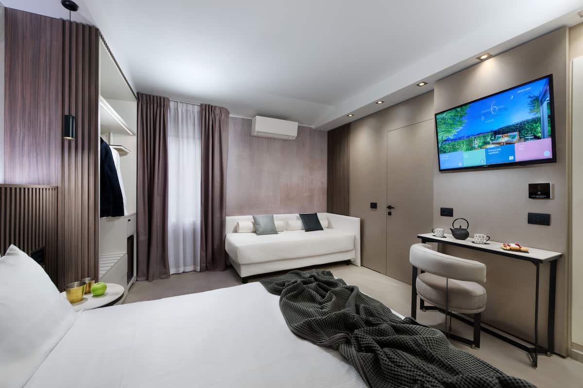 Ein modernes Hotelzimmer mit einem Bett, einer Couch, einem Schreibtisch und einem Fernseher.