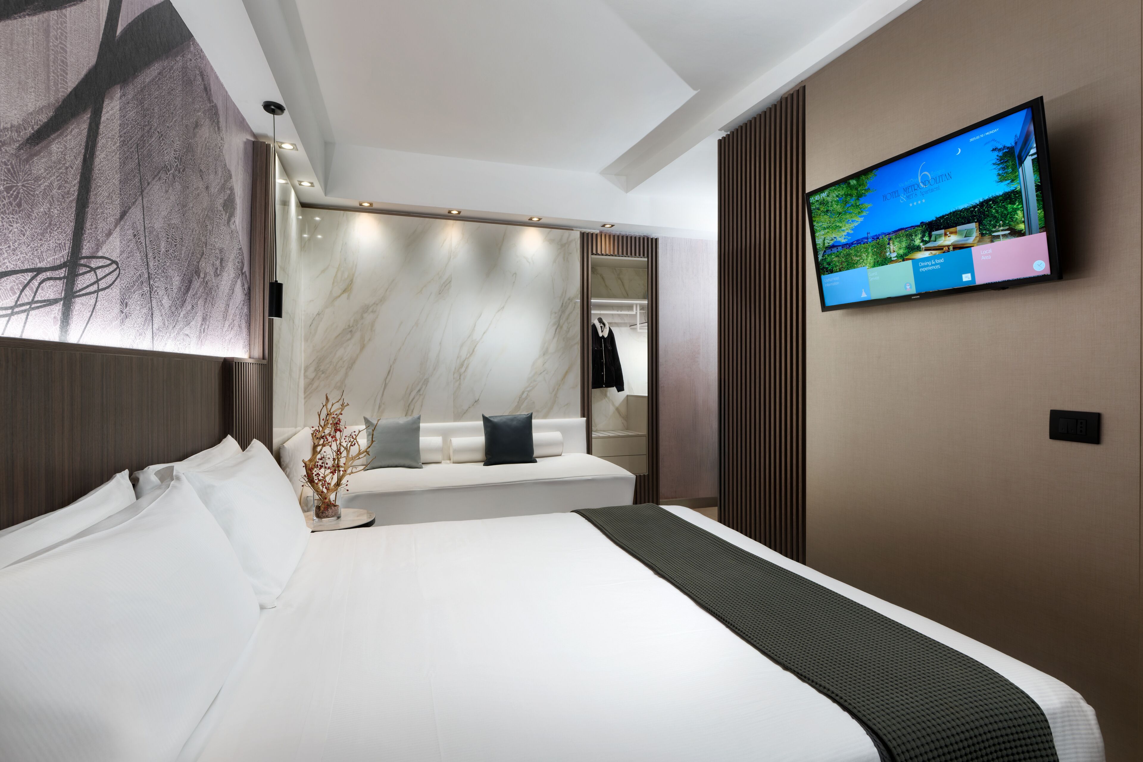 Una habitación de hotel moderna con una cama grande, un televisor montado en la pared y un espejo amplio.