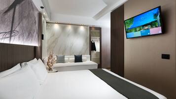 Una habitación de hotel moderna con una cama grande, un televisor montado en la pared y un espejo amplio.