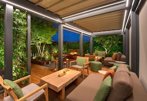 An outdoor patio area with wooden furniture, a cushioned sofa, and a dining table. - Hotel Metropolitan (Bologna)