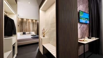 Une chambre à coucher moderne avec un lit, une table de chevet et un téléviseur fixé au mur.