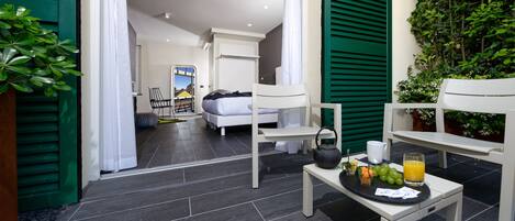 Una habitación de hotel moderna con una cama, una mesita con provisiones para el desayuno y vistas de la ciudad a través de una ventana.