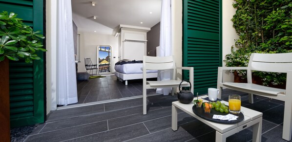 Una habitación de hotel moderna con una cama, una mesita con provisiones para el desayuno y vistas de la ciudad a través de una ventana.