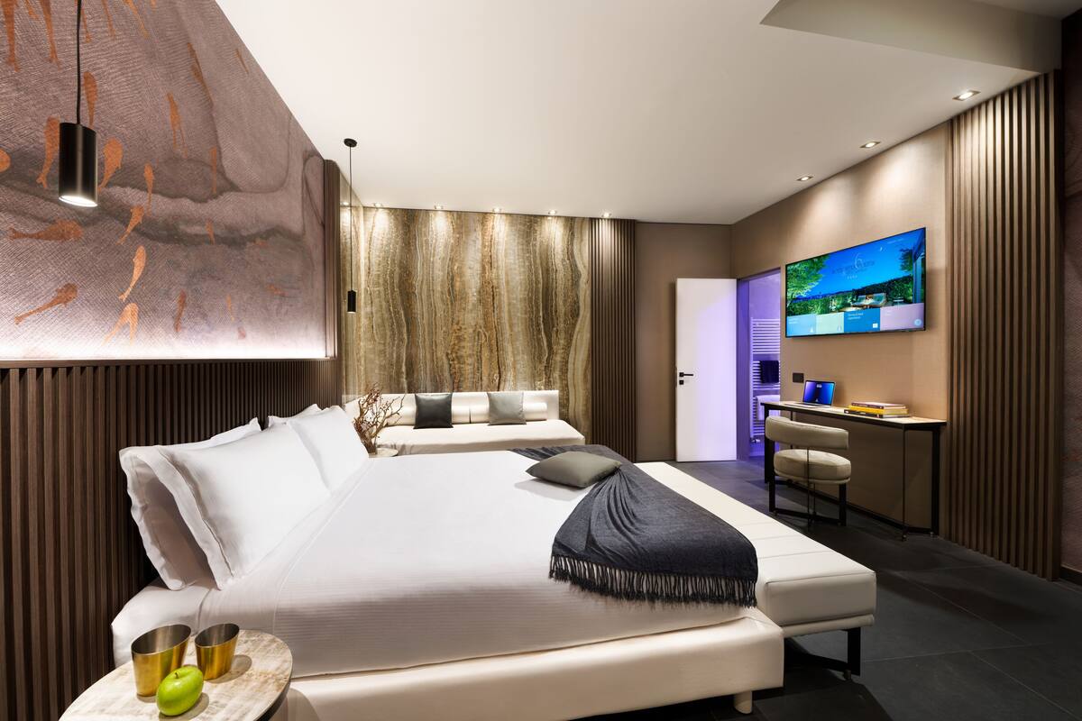 Ein modernes Hotelzimmer mit einem großen Bett, einem Schreibtisch und einem Fernseher.