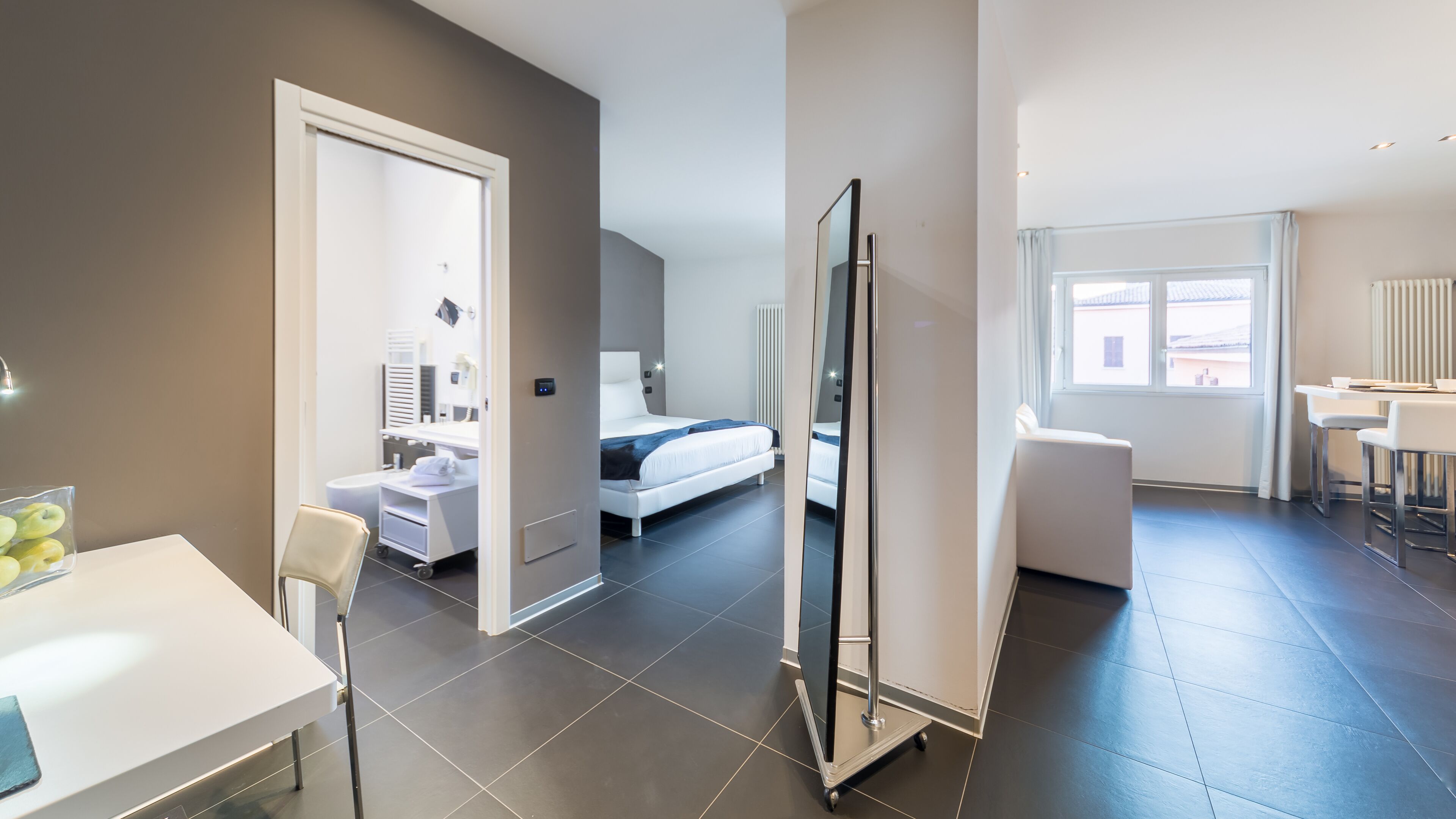 Een moderne hotelkamer met een bed, een bureau, een stoel en een zithoek.