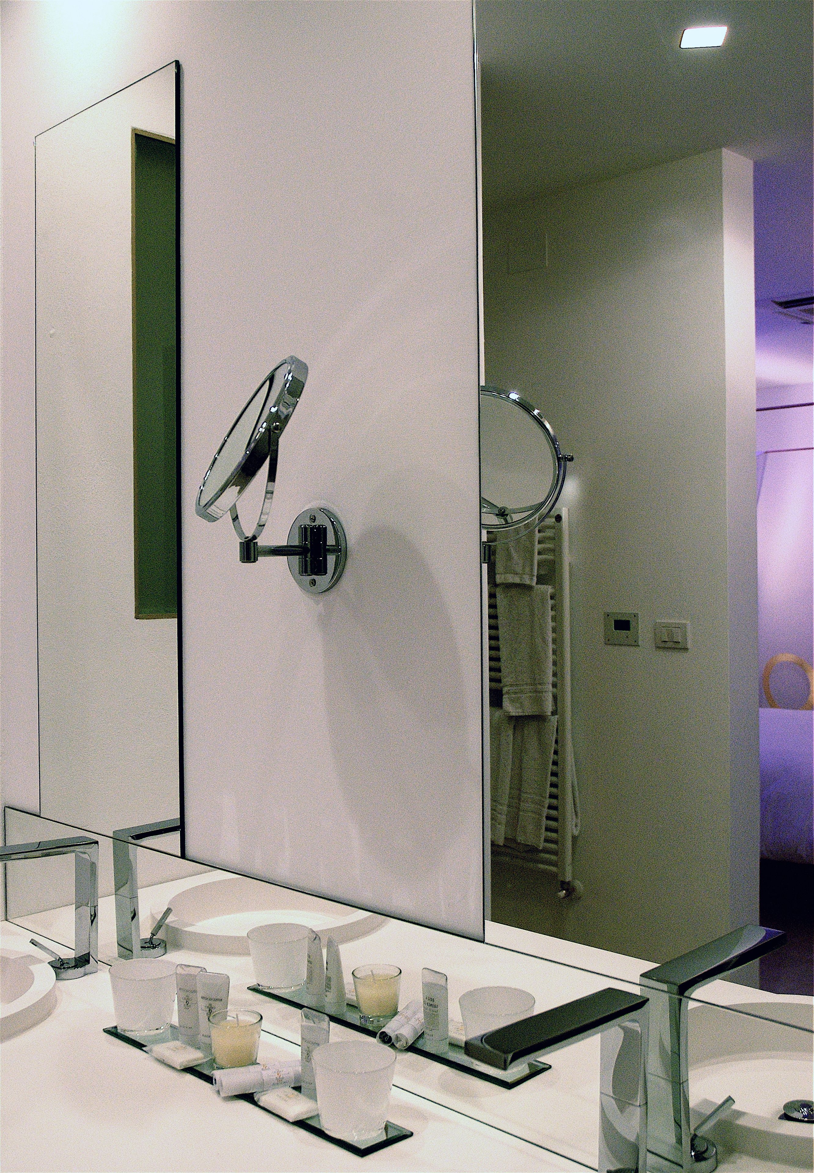 Un baño moderno con un espejo grande, cabina de ducha de vidrio y tocador con artículos de aseo.