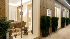 A hotel entrance with a modern design, featuring a reception area with wicker furniture and potted plants. - Hotel Metropolitan (Bologna)