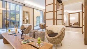 A spacious living area with a wooden coffee table, wicker chairs, and a view through large glass doors. - Hotel Metropolitan (Bologna)