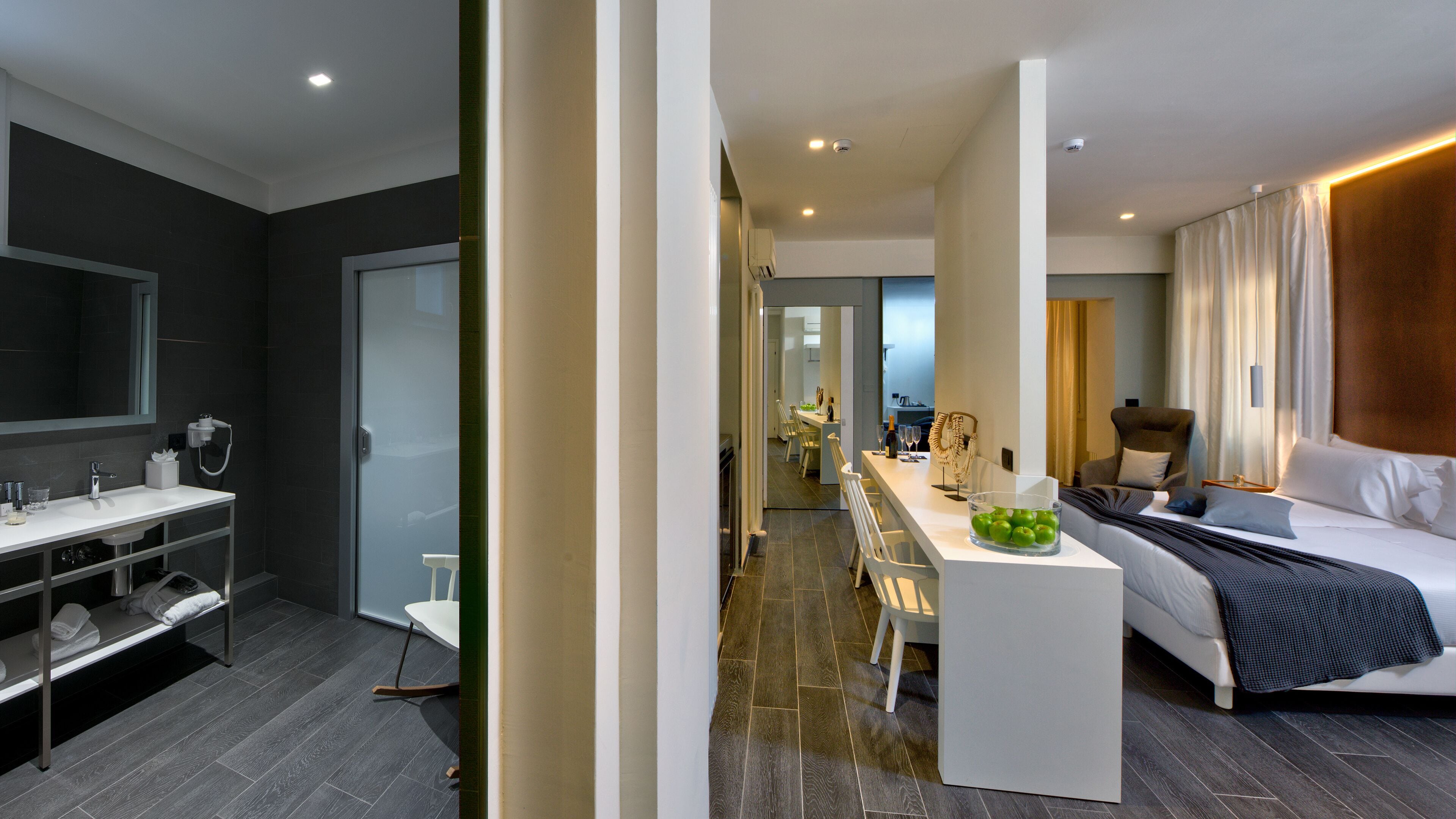 Habitación de hotel moderna con una cama grande, baño independiente, zona de comedor y vistas a la ciudad.