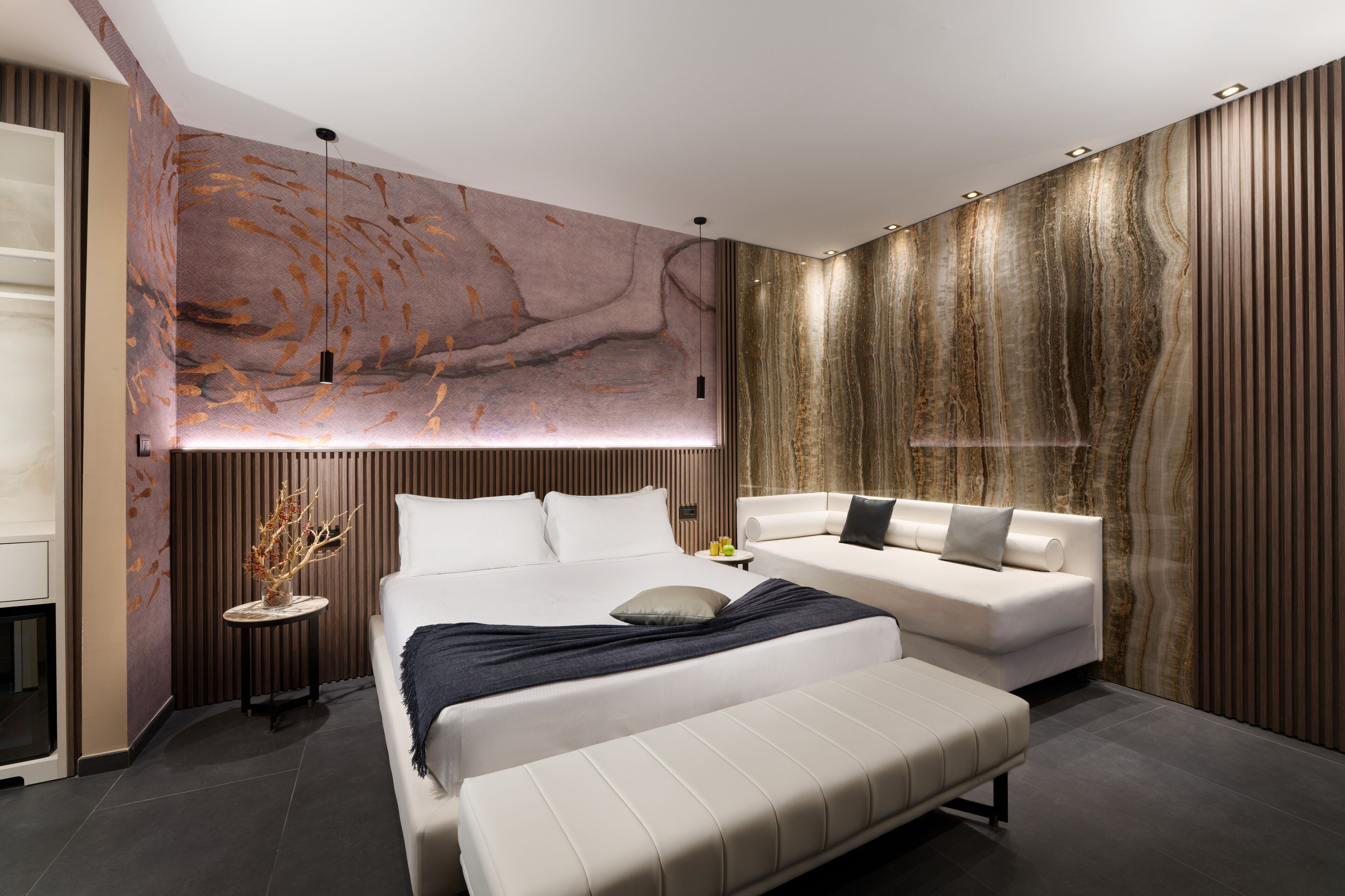 Una camera da letto moderna con un letto grande, un divano e una parete decorativa.