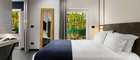 Un dormitorio moderno con una cama grande, una mesita de noche, un espejo y vistas a un espacio exterior verde.