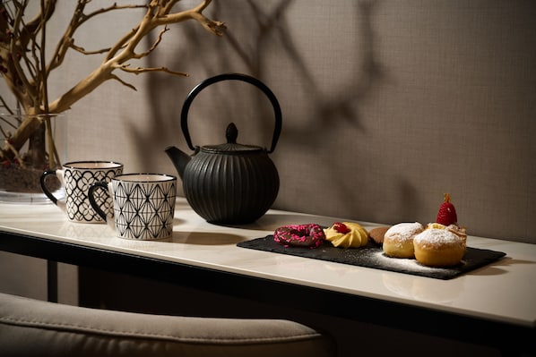 A table with a tea set, two patterned cups, a teapot, and pastries on a black slate. - Hotel Metropolitan (Bologna)