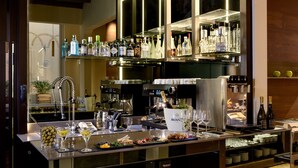 A bar area with a variety of liquor bottles, glasses, and a selection of food items on the counter. - Hotel Metropolitan (Bologna)