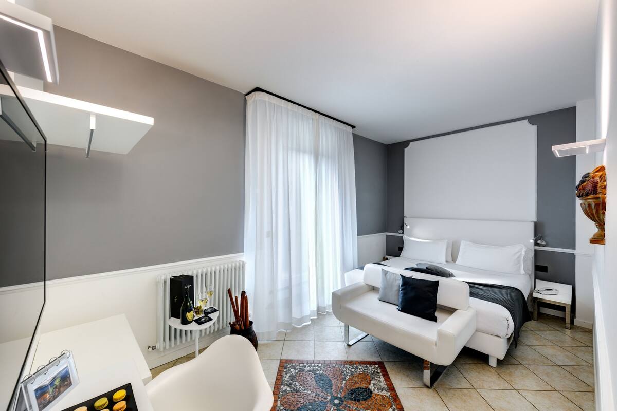 Ein modernes Hotelzimmer mit einem Bett, einem weißen Sofa, einem kleinen Tisch und einer Heizung.