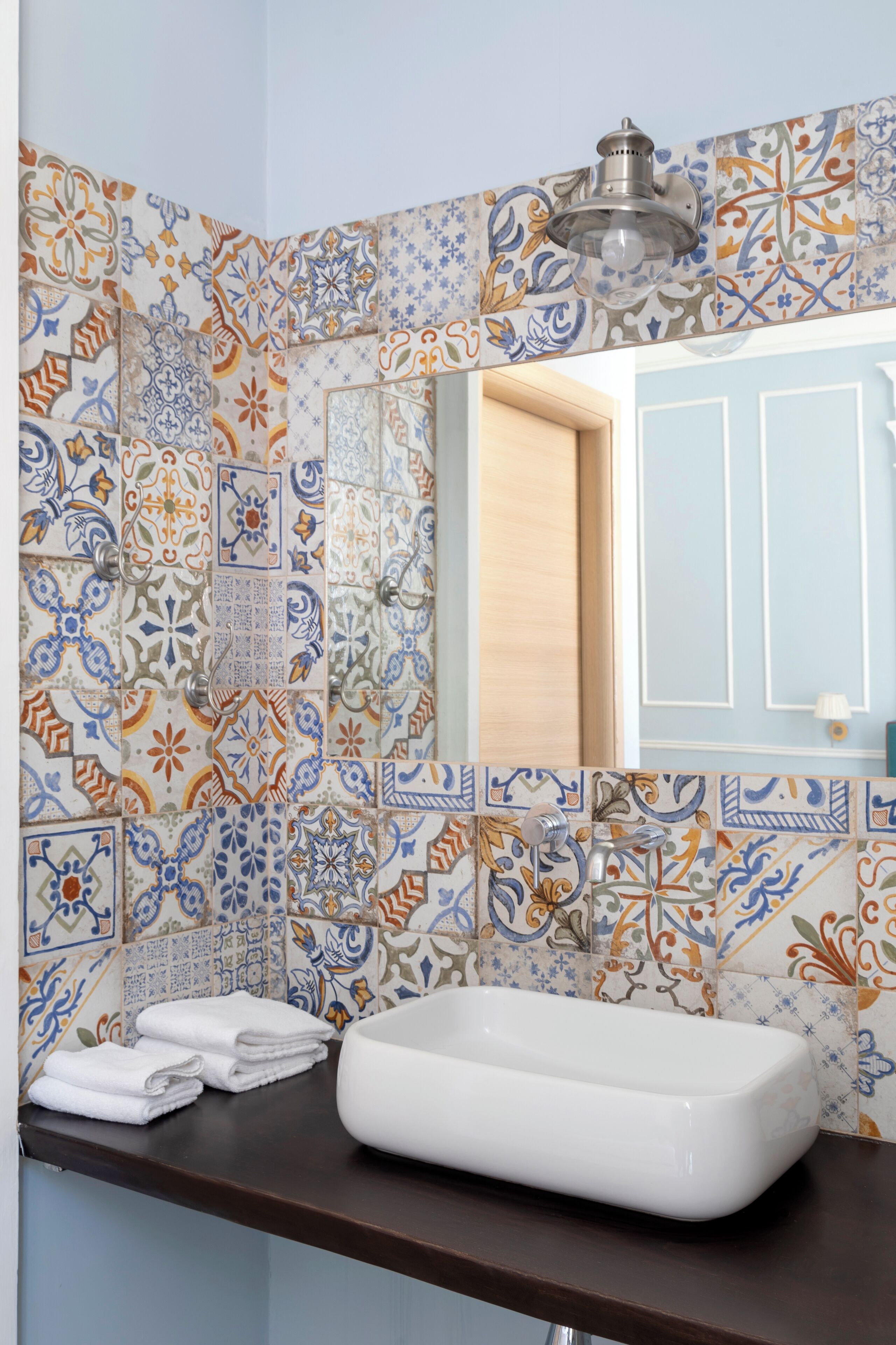 Un baño con salpicadero de azulejos, un lavabo y un espejo.