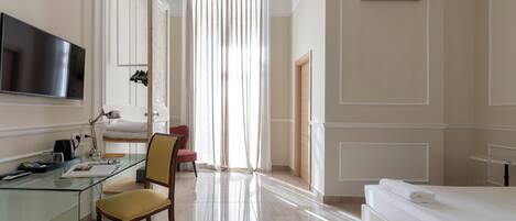 A hotel room with a glass desk, a chair, a bed, a TV, and an air conditioning unit.