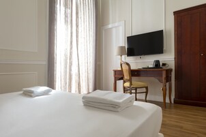 Hotelkamer met een bed, een bureau met stoel, een televisie aan de muur en een kledingkast.