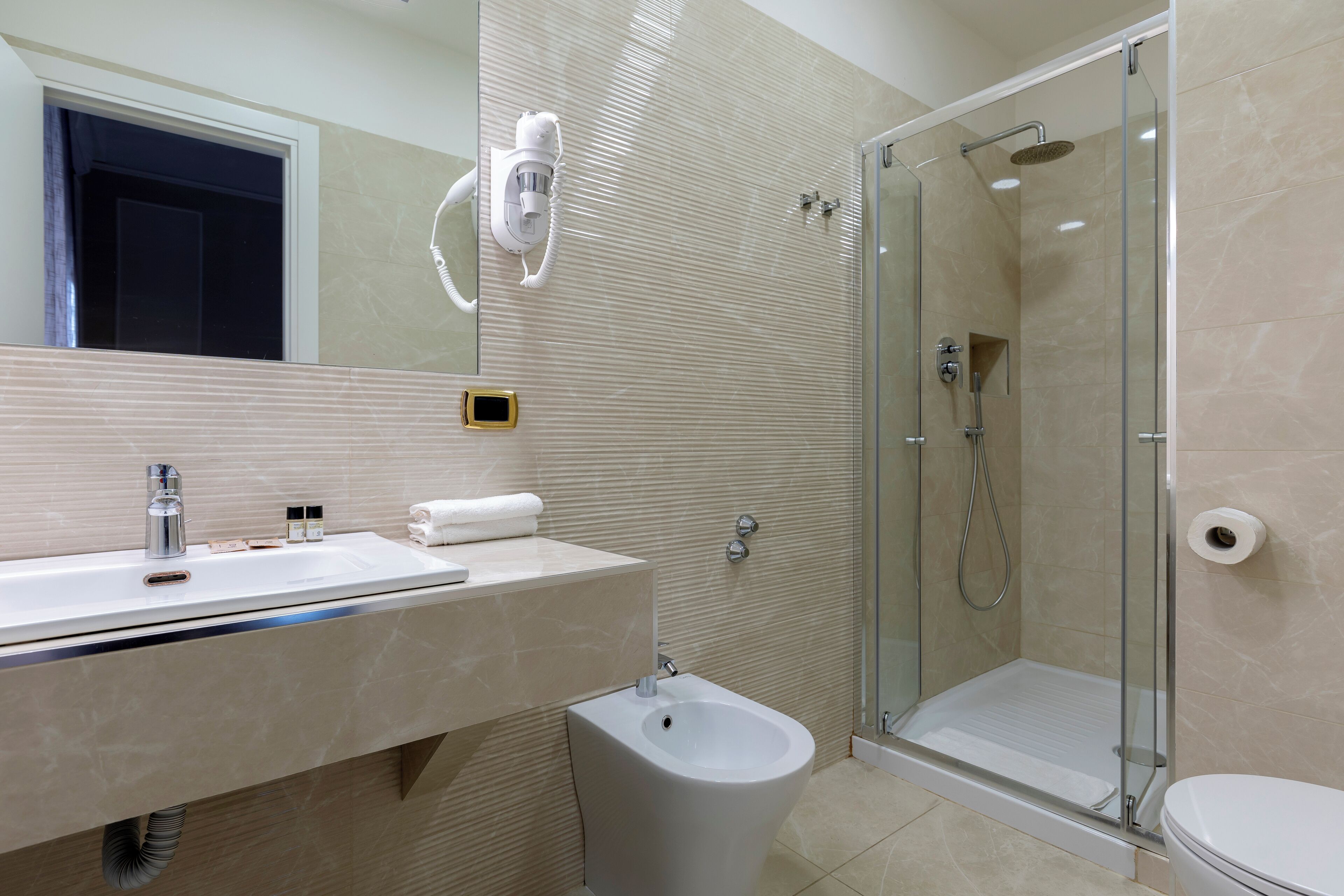 Une salle de bain moderne avec une douche à parois de verre, un bidet et un lavabo avec un miroir au-dessus.