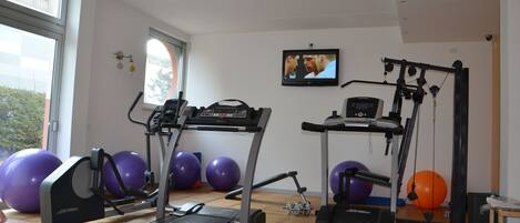 A gym with treadmills, elliptical machines, and exercise balls.