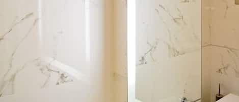 A bathroom with marble walls and a large mirror.
