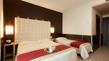 A hotel room with two beds, a bedside table with a lamp, and a tray with breakfast items.