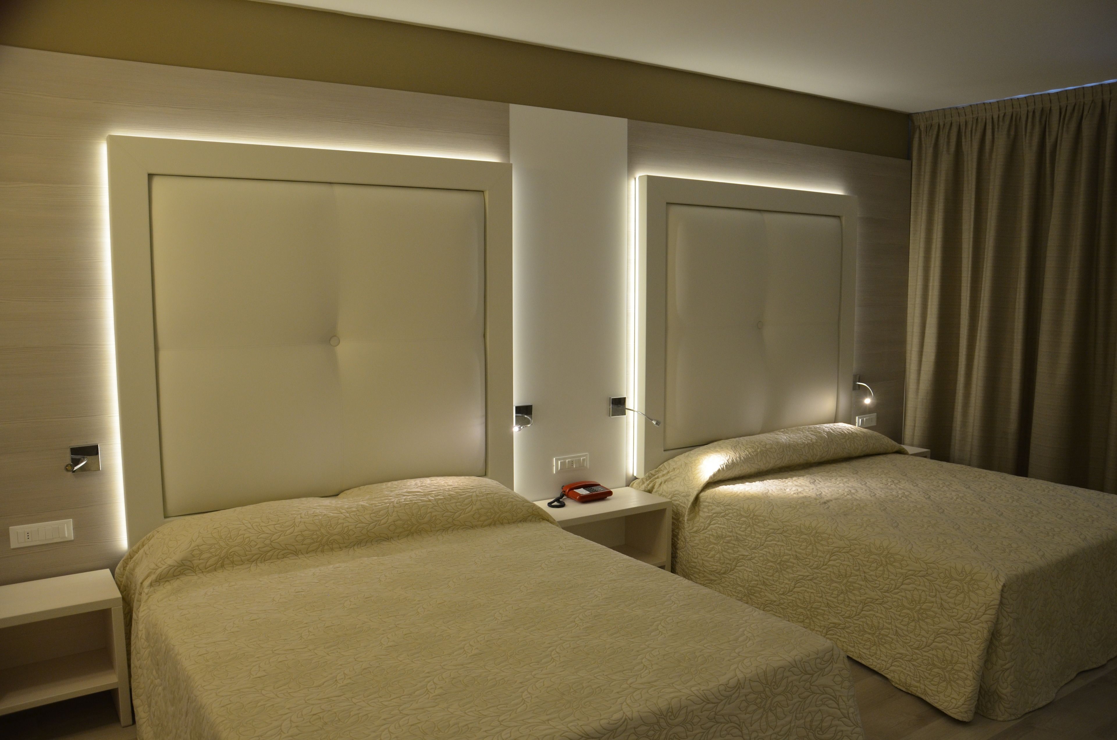 Ein Hotelzimmer mit zwei Einzelbetten, einem Nachttisch mit Lampe und einem Spiegel.