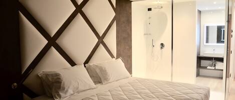 A modern bedroom with a large bed, a built-in wardrobe, and a shower area.