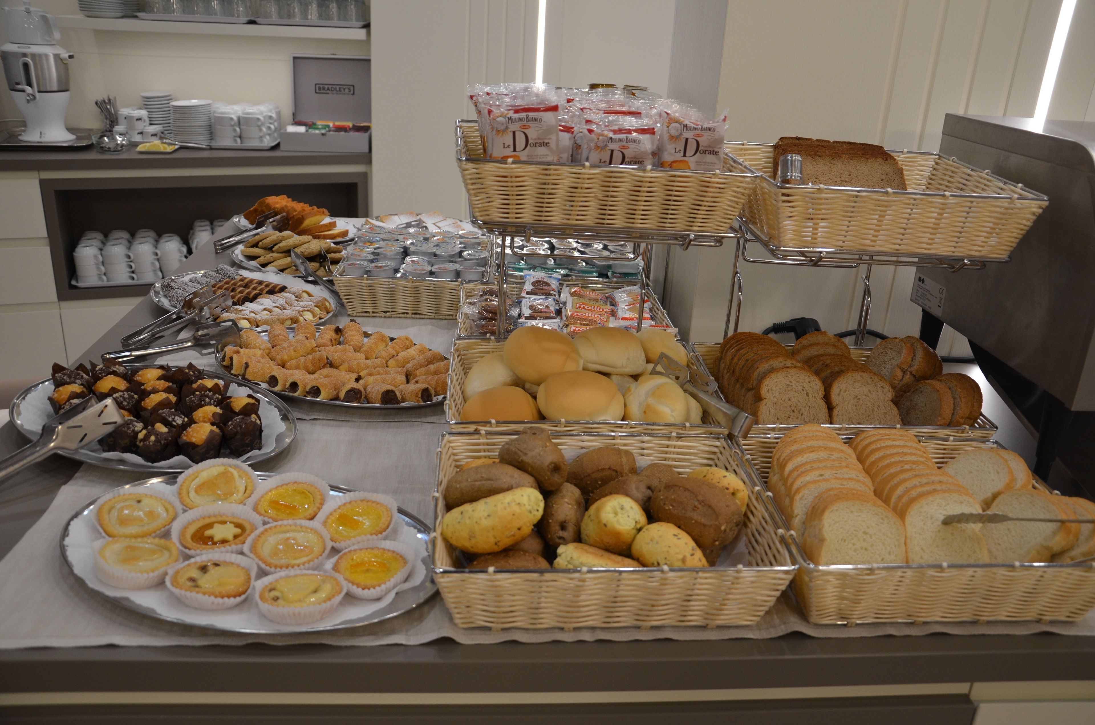 Ein Buffet mit verschiedenen Speisen, darunter Backwaren, Brot und Sandwiches.